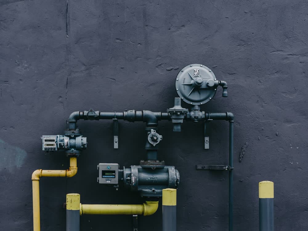 Water heater supply pipework mounted on a dark wall